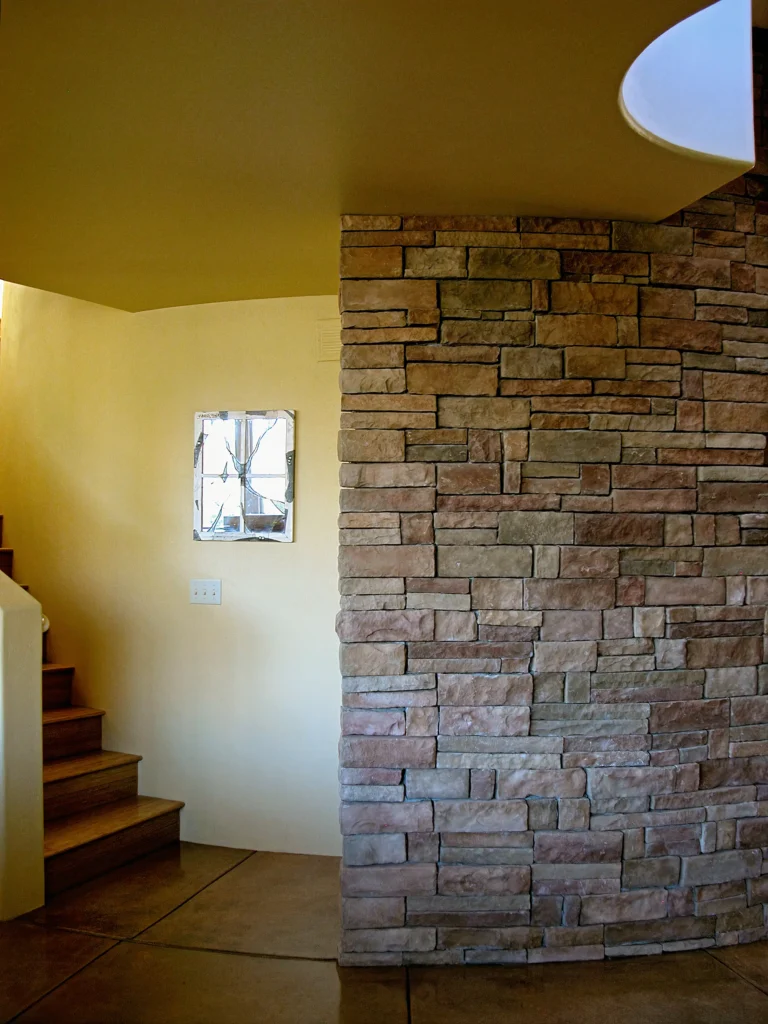 Interior view of a stacked-stone feature wall next to a curved stairway.