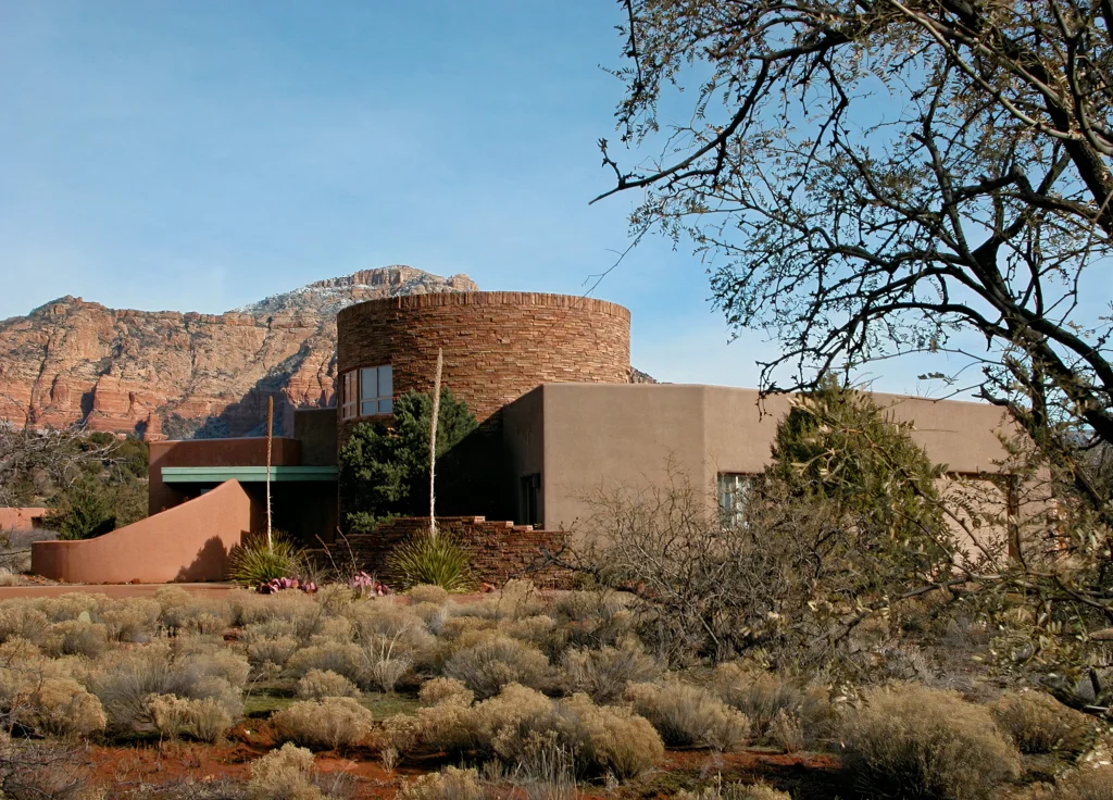 Exterior view of an adobe and stone Sedona home surrounded by native desert vegetation.