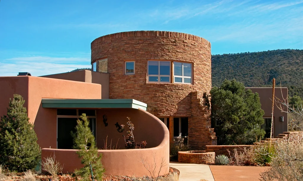 Custom home designed by Sedona architect Paul Cate featuring a curved adobe wall and stone tower.
