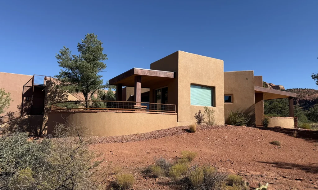 Stucco and stone Sedona home with a covered patio facing the surrounding red rock terrain.