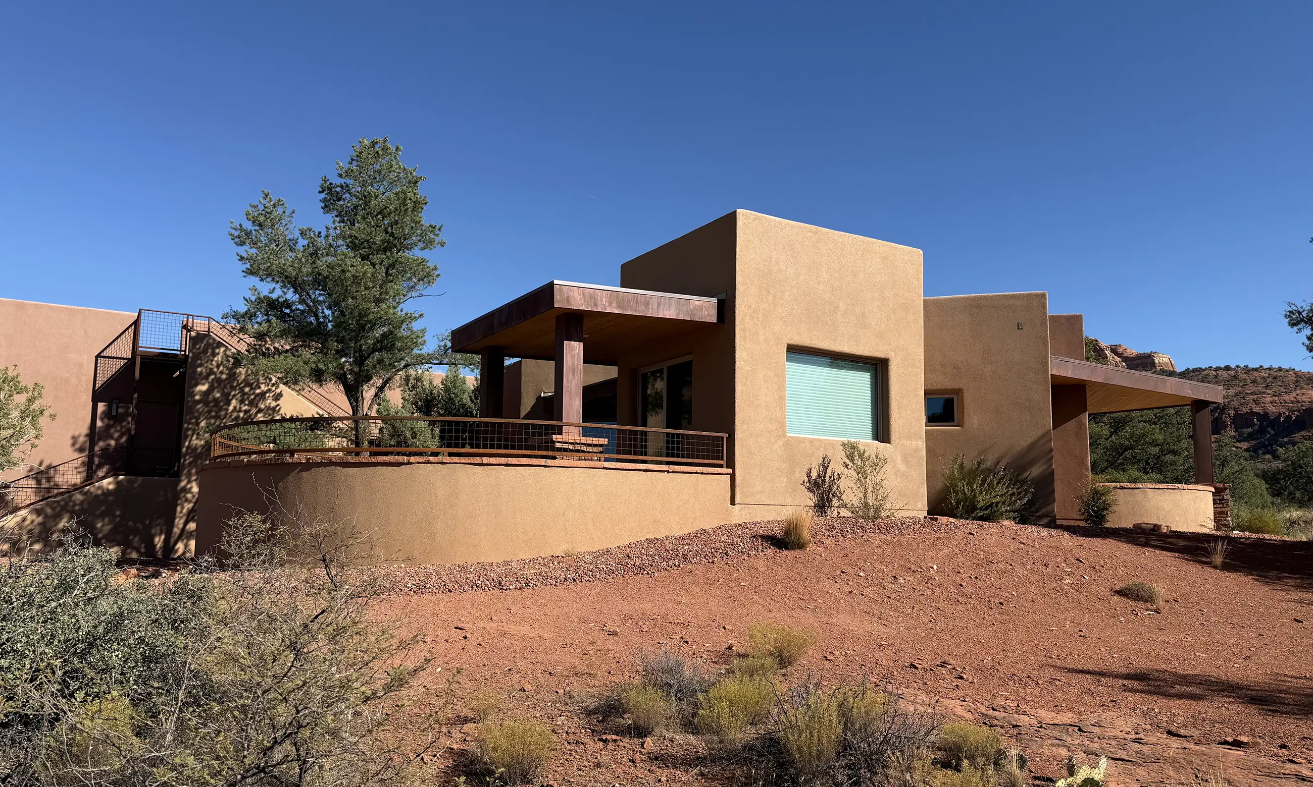 Stucco and stone Sedona home with a covered patio facing the surrounding red rock terrain.