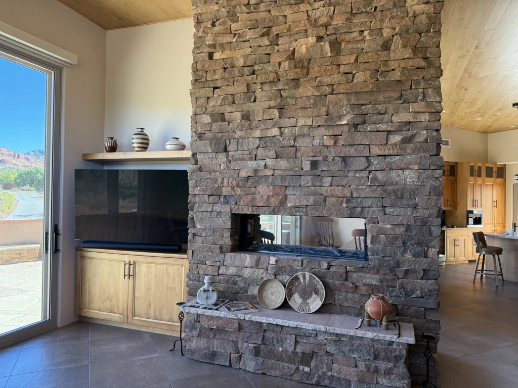 Stone fireplace wall separating living spaces with a window view toward the Sedona landscape.