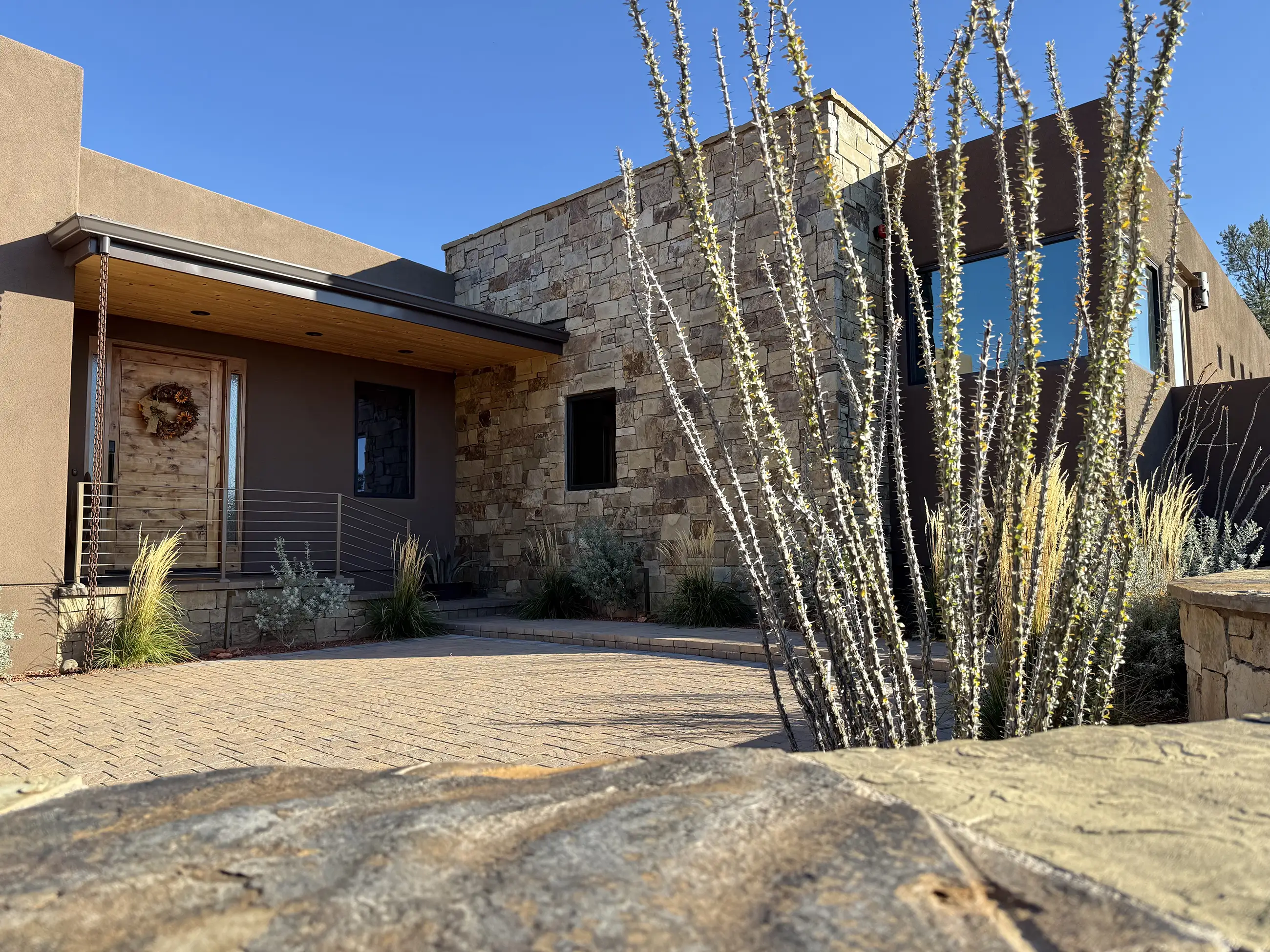 Front entry of a custom Sedona home designed by architect Paul Cate, with stone and stucco walls and desert landscaping.