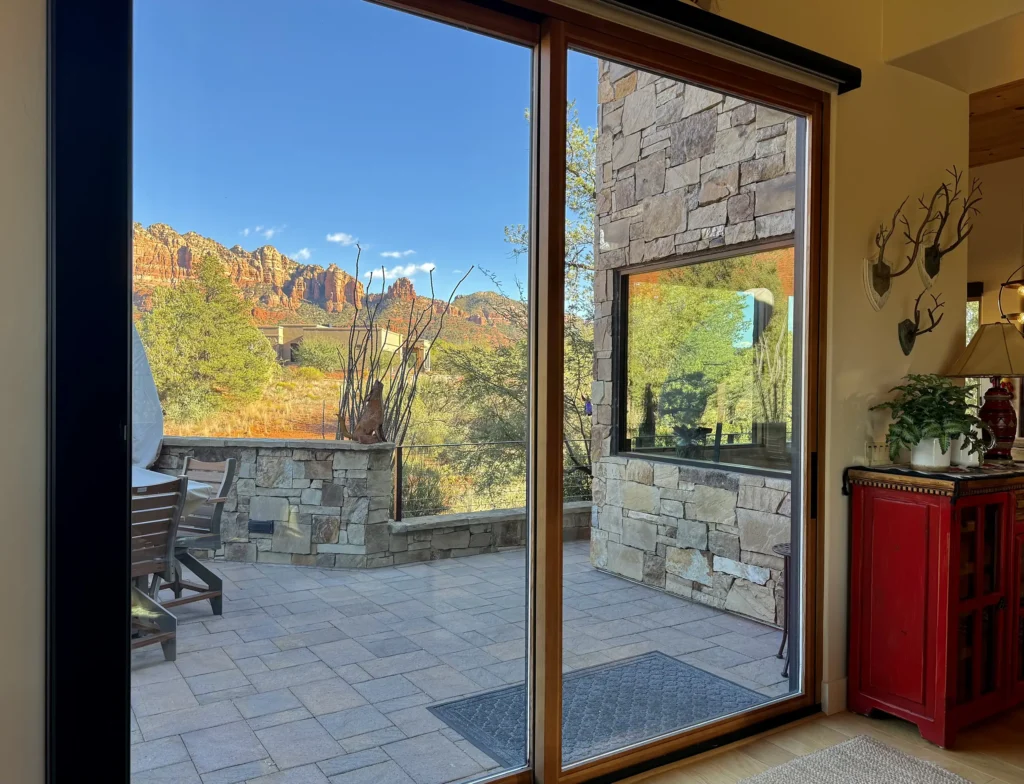 Sliding glass doors from the living area opening to a stone patio with views of the red rocks.
