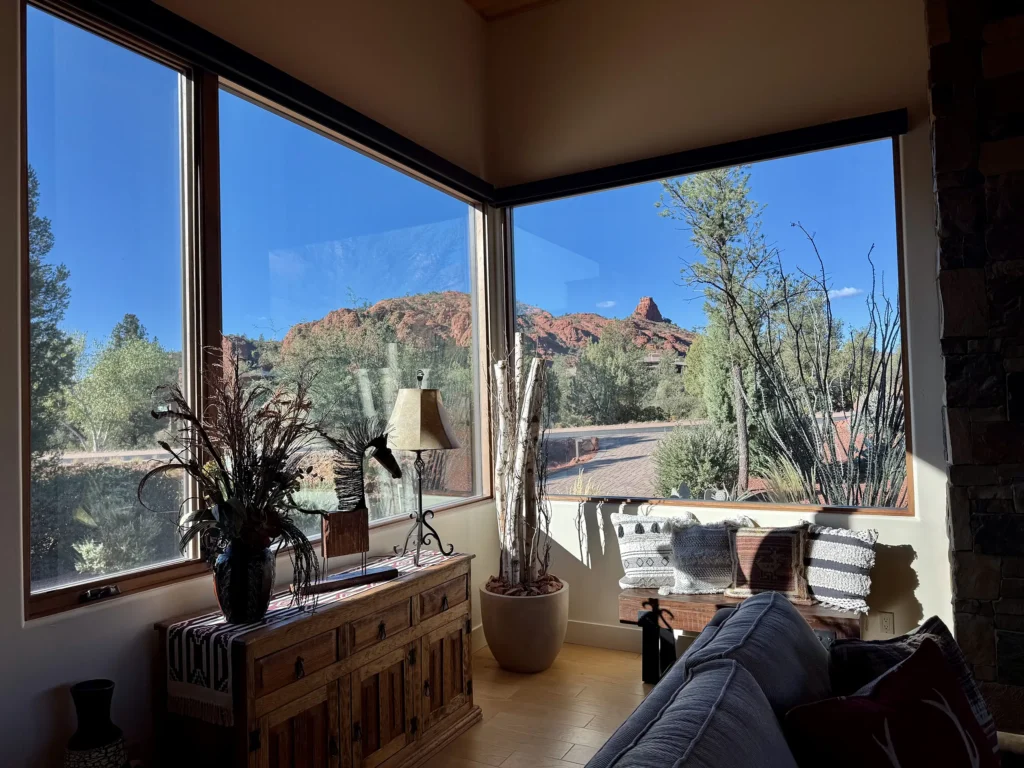 Corner sitting area with console table and bench under large windows looking toward red rocks.