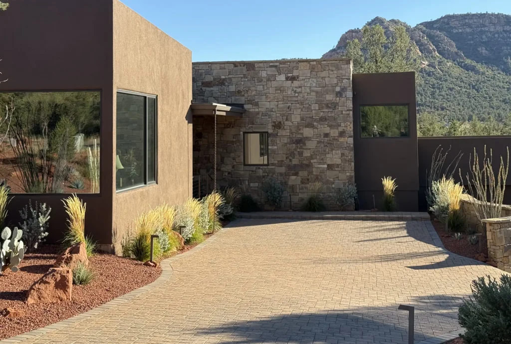 Driveway view of a contemporary residence with a central stone entry volume and stucco wings.