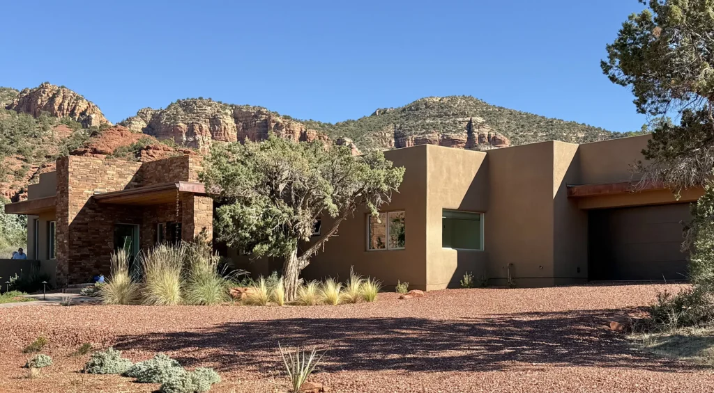 Contemporary stucco and stone Sedona residence set against red rock hills and natural desert landscaping.