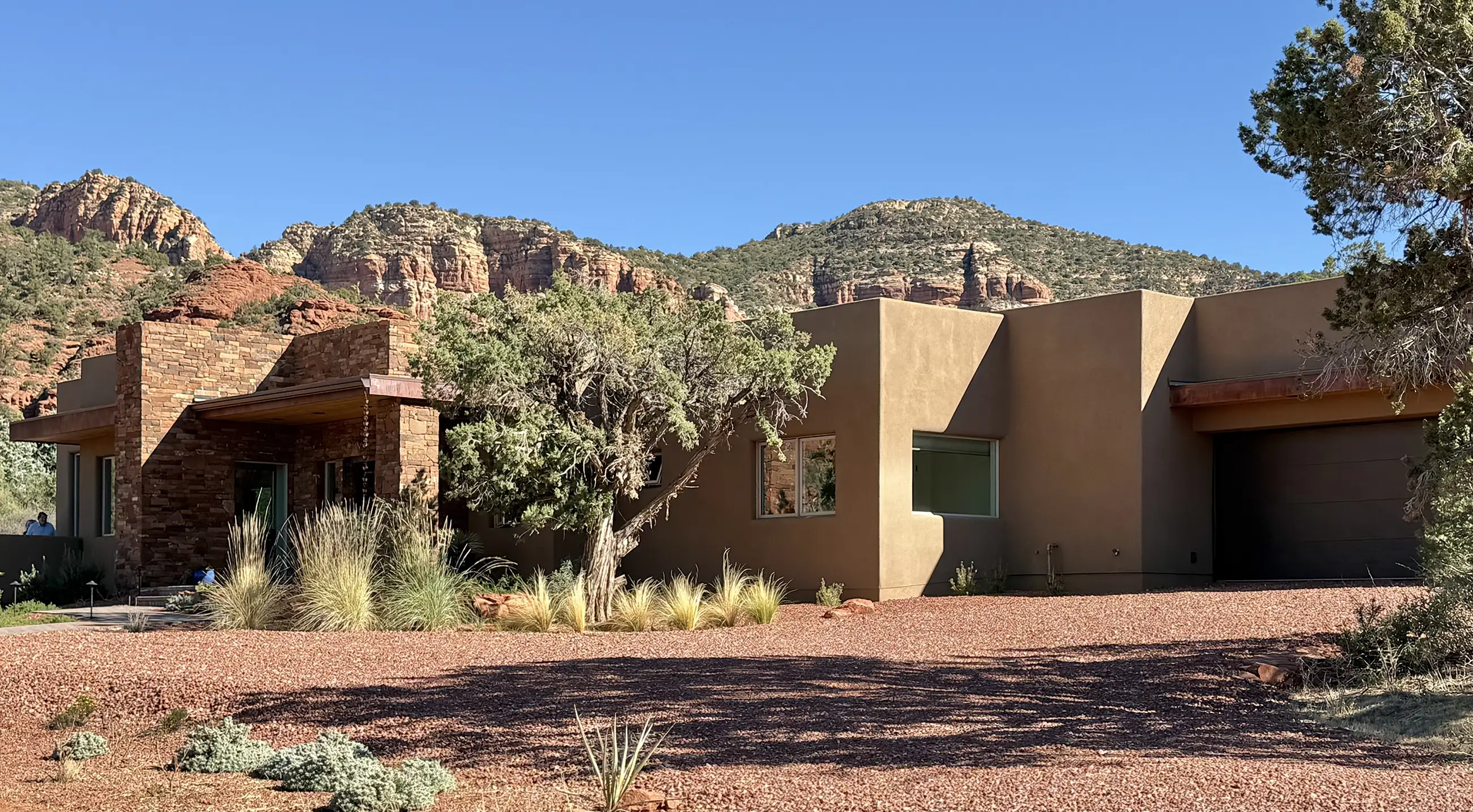 Contemporary stucco and stone Sedona residence set against red rock hills and natural desert landscaping.