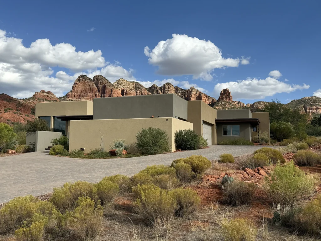 Contemporary desert home designed by architect Paul Cate with flat-roof stucco volumes and red rock mountains in the background.