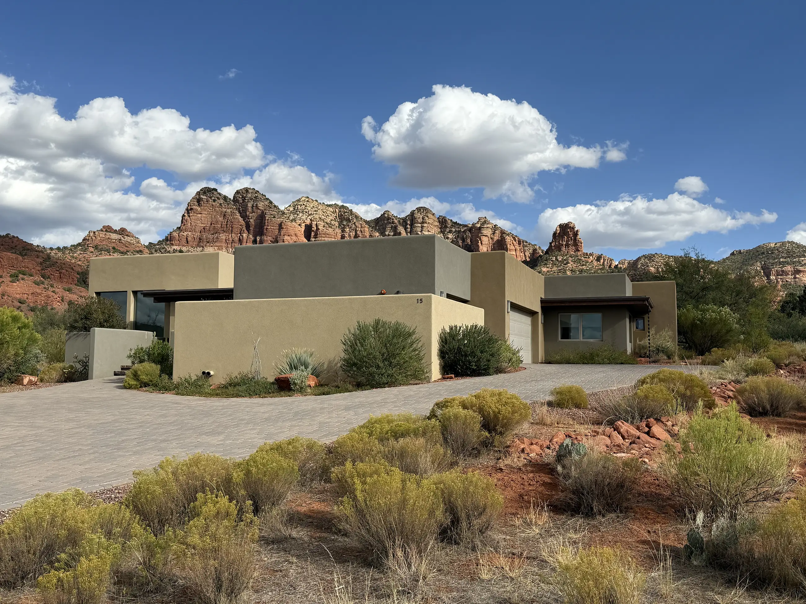 Contemporary desert home designed by architect Paul Cate with flat-roof stucco volumes and red rock mountains in the background.