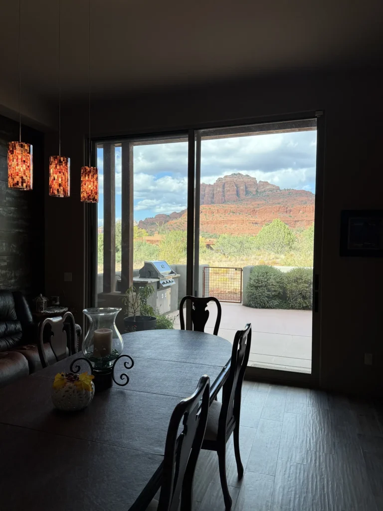 Dining room with sliding glass doors opening to a patio and dramatic Cathedral Rock view beyond.