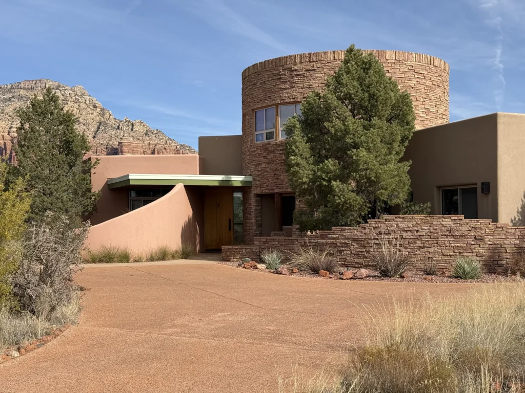 Custom home designed by Sedona architect Paul Cate featuring a curved adobe wall and stone tower.