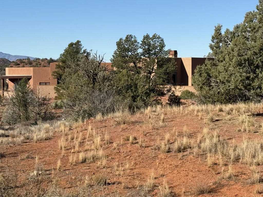 Sedona residence partially hidden among juniper trees and natural desert vegetation.
