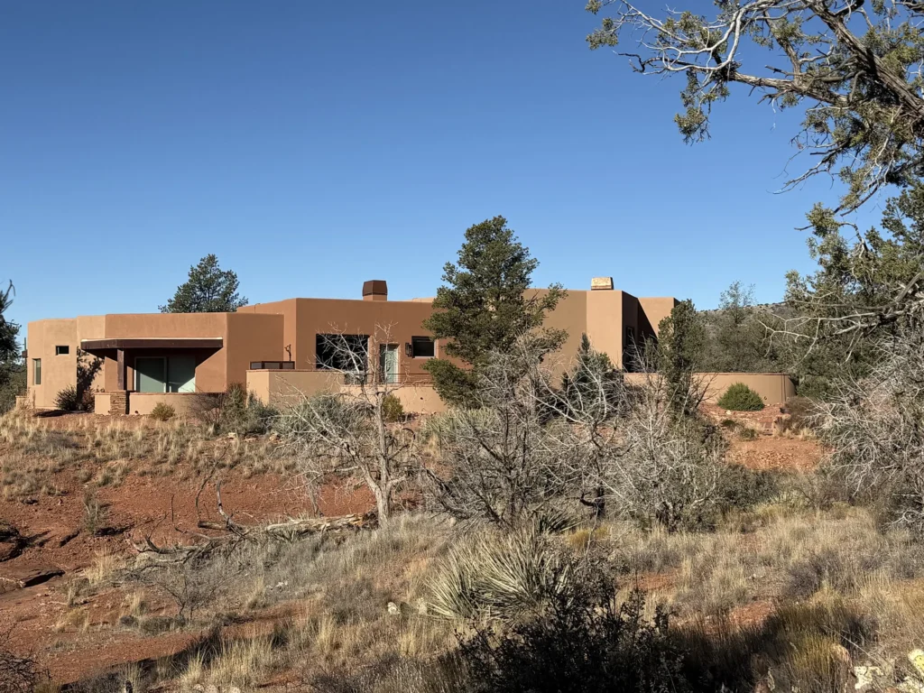 Sedona residence partially hidden among juniper trees and natural desert vegetation.