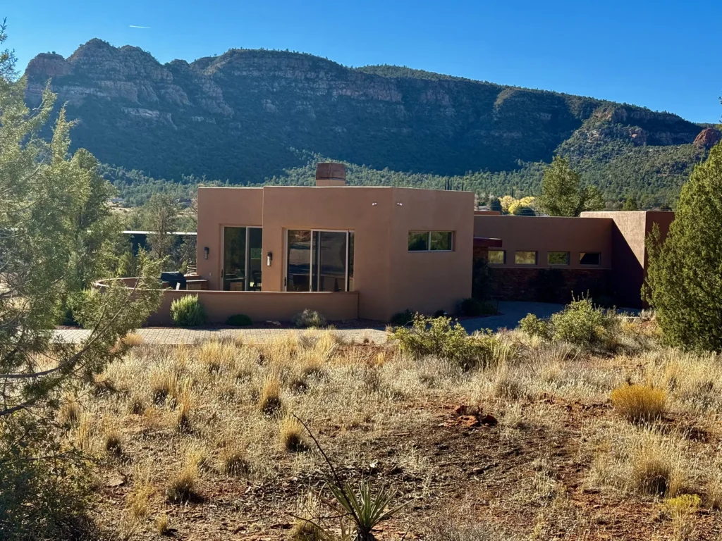 Sedona desert home with broad windows and native landscaping along a curved driveway.
