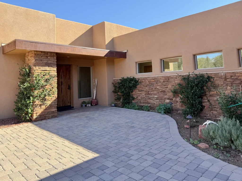 Front courtyard of gorgeous home featuring a stone column, wood door, and stucco façade.