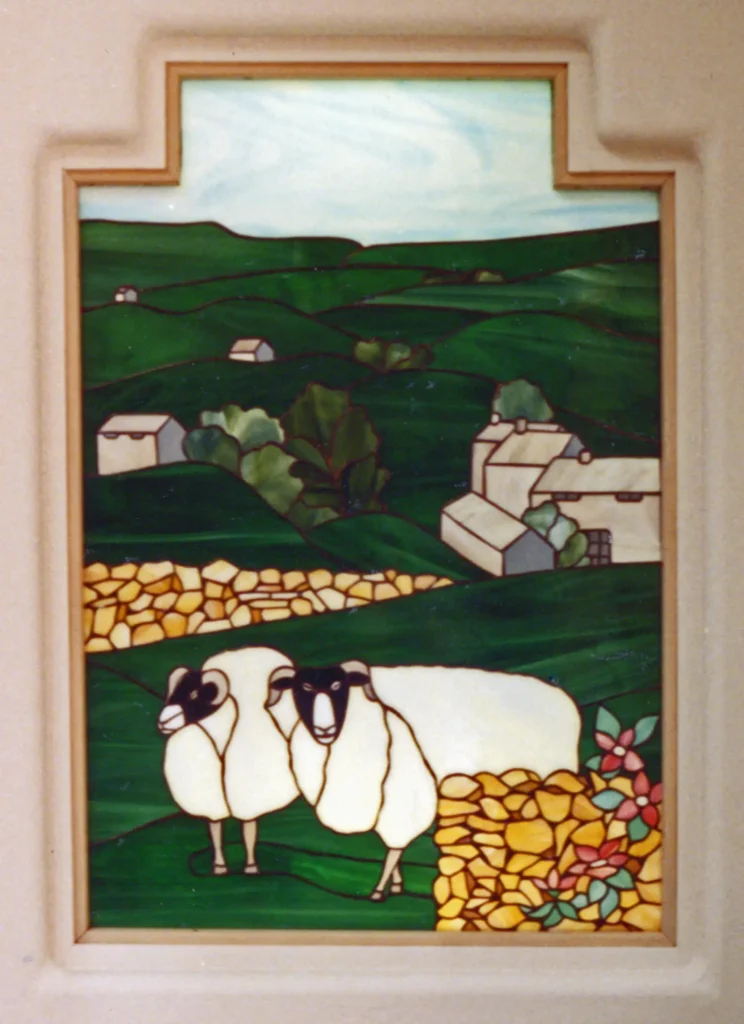Stained glass window created by Monika Cate in a Paul Cate designed home showing sheep in a green hillside landscape.